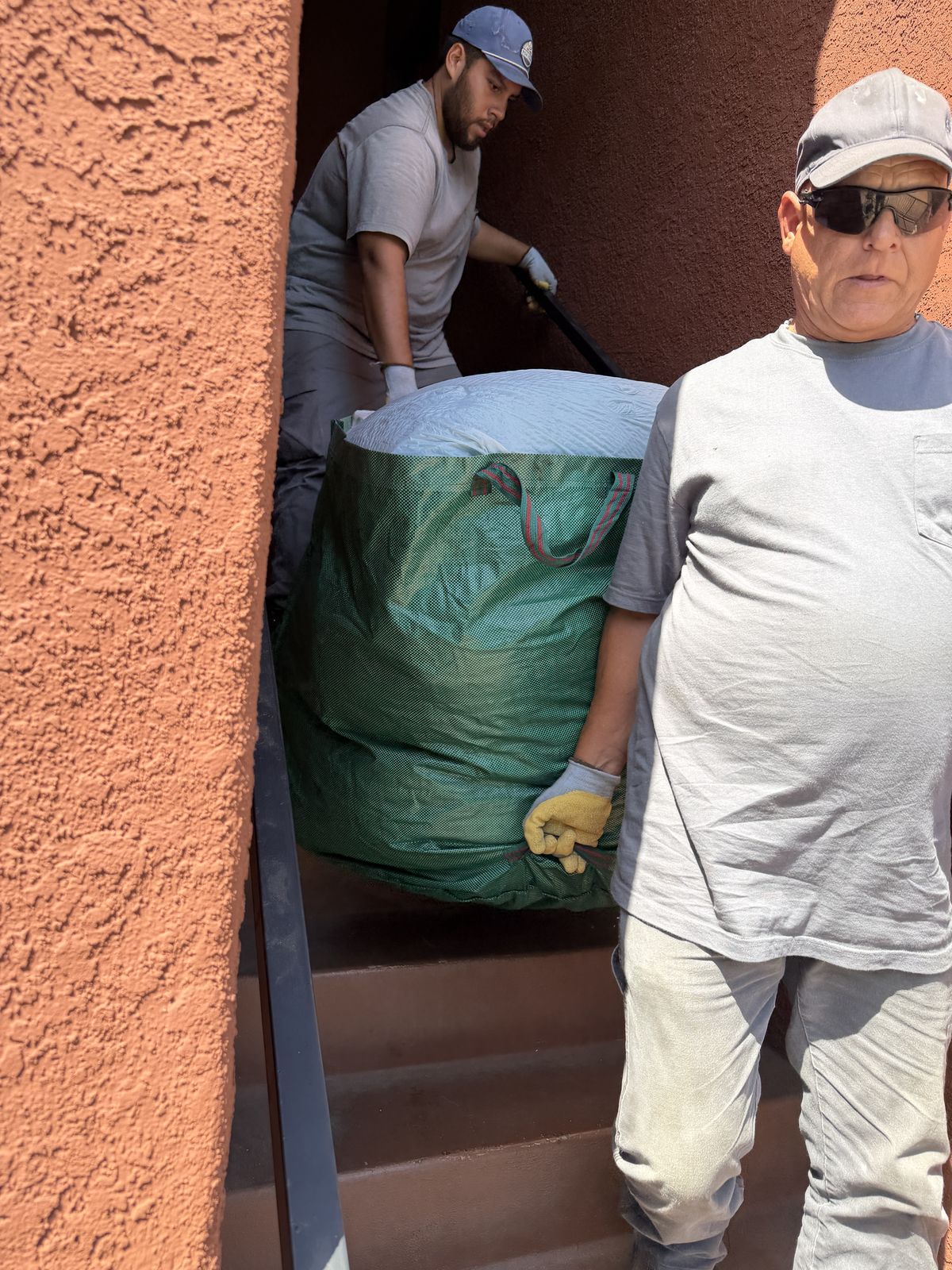 Fred's crew carrying a bag of household trash down stairs on a full-service San Diego junk removal