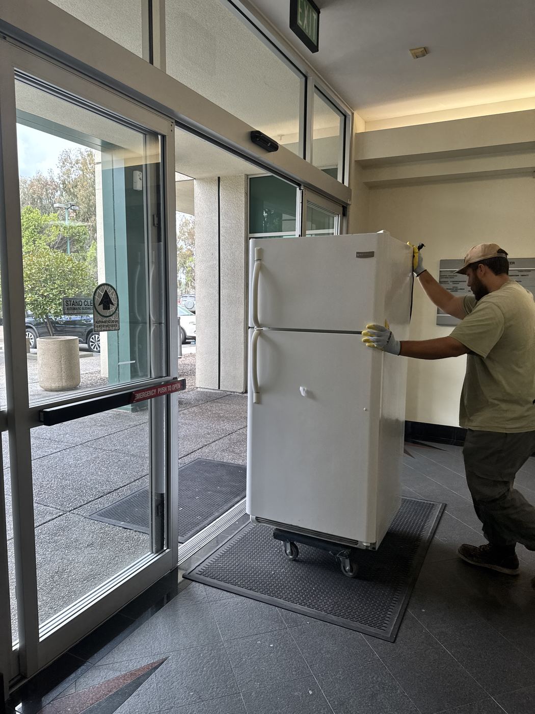 Fred's junk removal crew rolling a refrigerator out of a San Diego building lobby